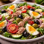 Салат з тунцем, яйцем, овочами та оливками з заправкою з оливкової олії